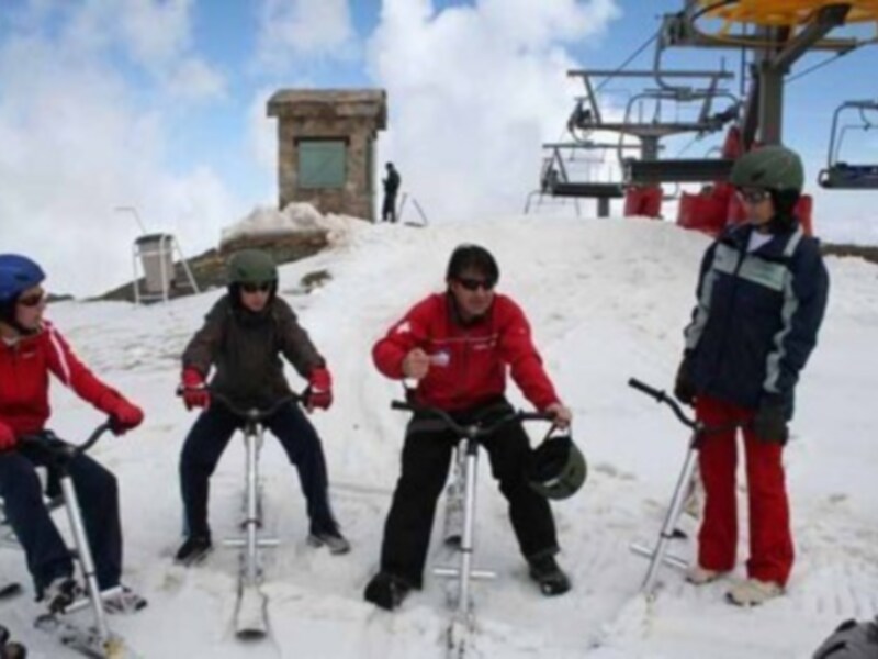 Personas montando bicicletas de nieve en la cima de una montaña nevada.