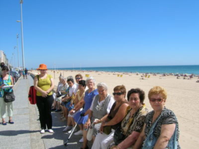 Grupos de personas disfrutando de un día soleado en la playa junto al mar.