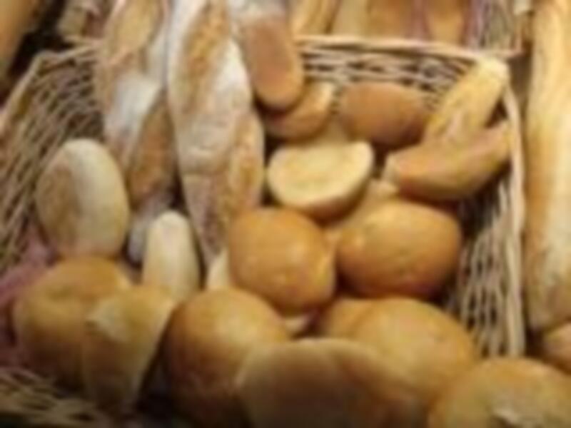 Un cesto lleno de panes variados, desde panes planos hasta panes redondos y tostados.