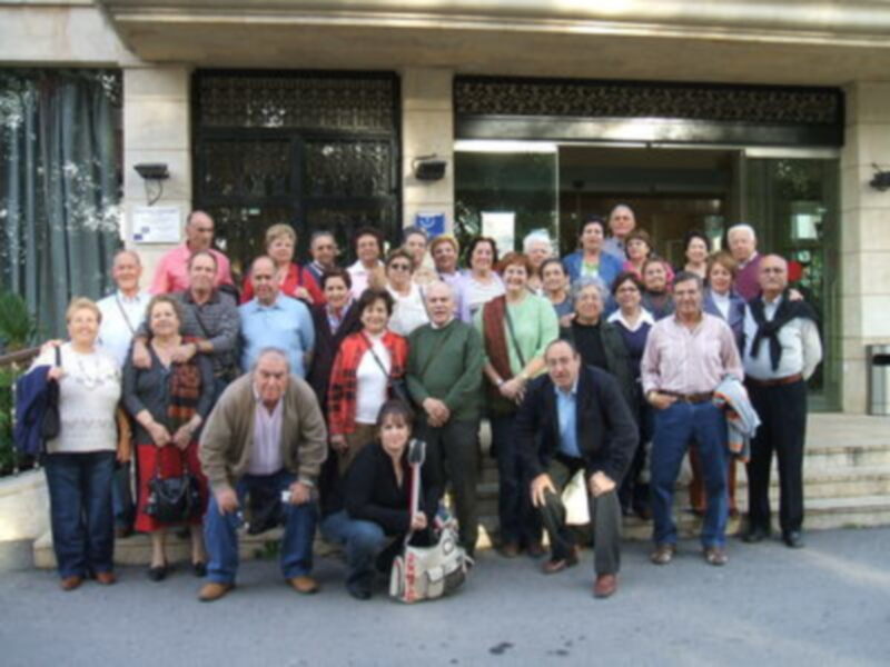 Grupo de personas posando para una foto en el exterior de un edificio con ventanas y detalles arquitectónicos.