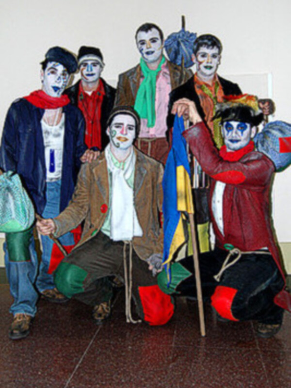 Grupo de personas vestidas como payasos con maquillaje y ropas coloridas, posando en un entorno interior.