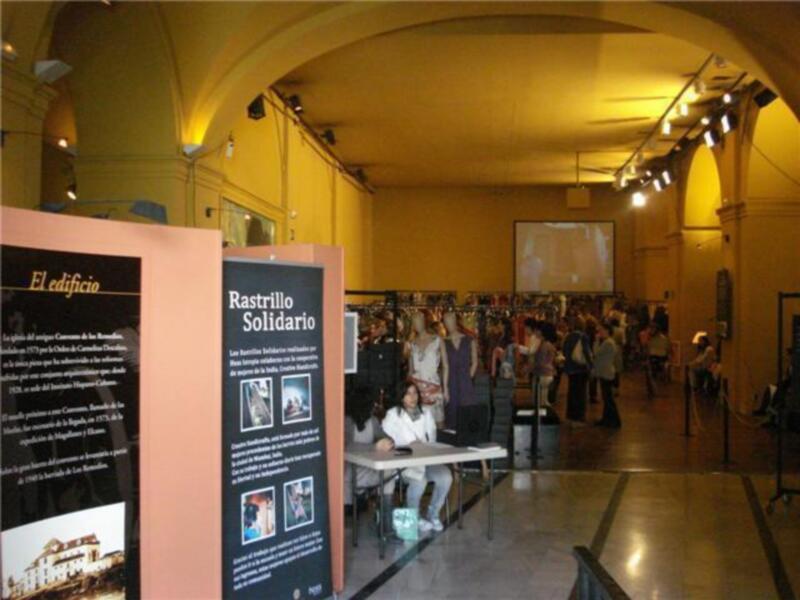 Exposición de arte en un museo con paneles informativos y visitantes observando obras de arte.