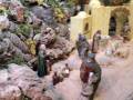 Figuras de escena de nacimiento en un entorno montañoso con animales y personajes vestidos con trajes medievales.