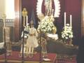 Estatua de la Virgen María con flores y velas en un altar ceremonial.