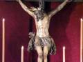 Un Cristo crucificado en una cruz, rodeado de velas y flores.