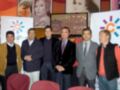 Grupo de personas posando frente a un fondo con imágenes de celebridades y logotipos de empresas.