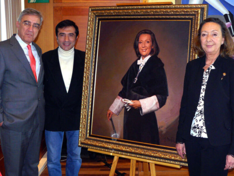 En el centro, una pintura muestra a una mujer con un vestido negro y corbata blanca. A su izquierda, dos hombres en trajes posan junto a la pintura; uno con corbata roja y el otro con camisa blanca. A la derecha, una mujer en traje negro mira hacia el espectador con un gesto amistoso. La escena está ambientada en una sala de conferencias, con elementos decorativos y un fondo que incluye una bandera.