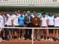 Equipo de tenis posando junto a autoridades en cancha de tenis.