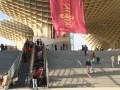 Escaleras de acceso a la Metropol Parasol, Sevilla, con gente subiendo y bajando y una bandera roja colgando en el centro.