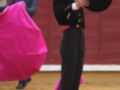 Un torero en traje de luces con mantón rosa en una plaza de toros.