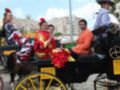 Personas vestidas con trajes típicos andaluces disfrutan de un viaje en carruaje durante una celebración cultural.