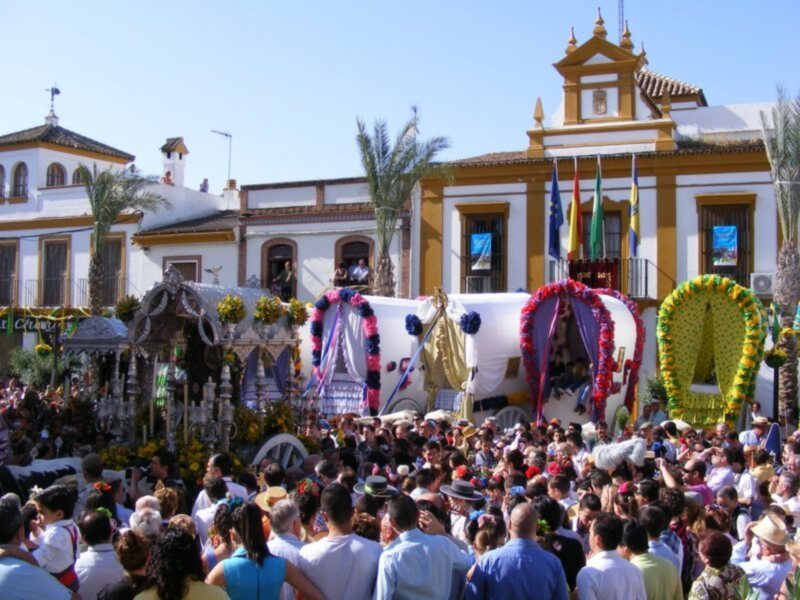Fiesta tradicional en España con carrozas decoradas y multitud celebrando en la plaza.