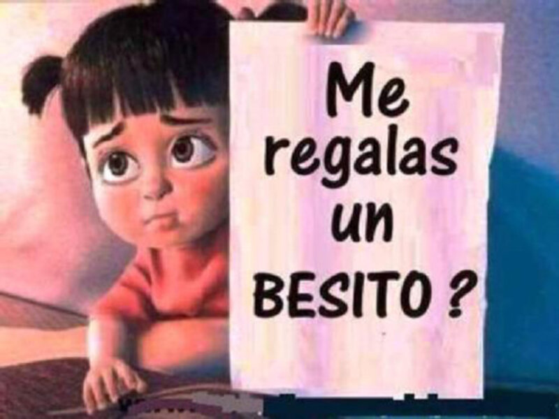 Una niña con una pancarta que dice "Me regalas un besito?" en la imagen.