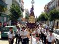 Desfile de una banda militar en una calle de la ciudad, con uniformes blancos y insignias doradas.