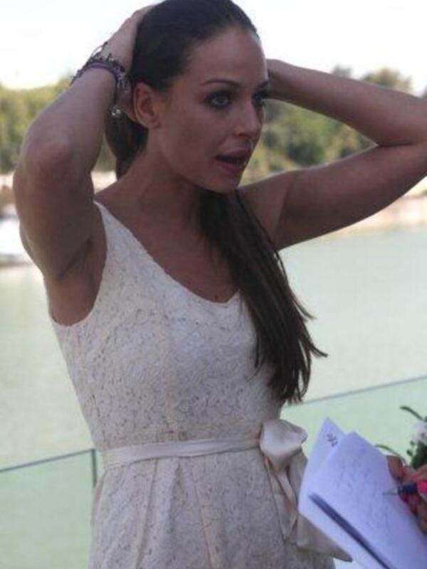 Una mujer con vestido blanco y cabello largo, posando en un entorno al aire libre.