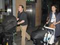 Una pareja llega al aeropuerto con equipaje y un cochecito de bebé.
