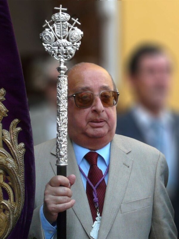 Persona con traje y bastón ornamental, probablemente participando en una procesión o ceremonia religiosa.