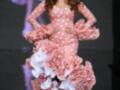Una modelo desfilando con un vestido de flamenca rosa con lunares y volantes en la falda, complementado con un tocado floral.