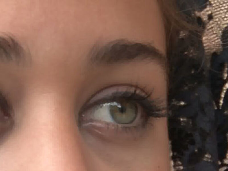 Ojos con maquillaje de ojos negros y pestañas largas, fondo de textura de encaje.