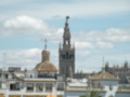 Vista panorámica de la Catedral de Sevilla, destacando su emblemática Giralda y el cielo nublado.