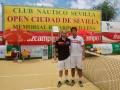 Dos tenistas posan en un campo de tenis con una gran pancarta que anuncia el Club Náutico Sevilla Open Ciudad de Sevilla Memorial Ricardo Villena.