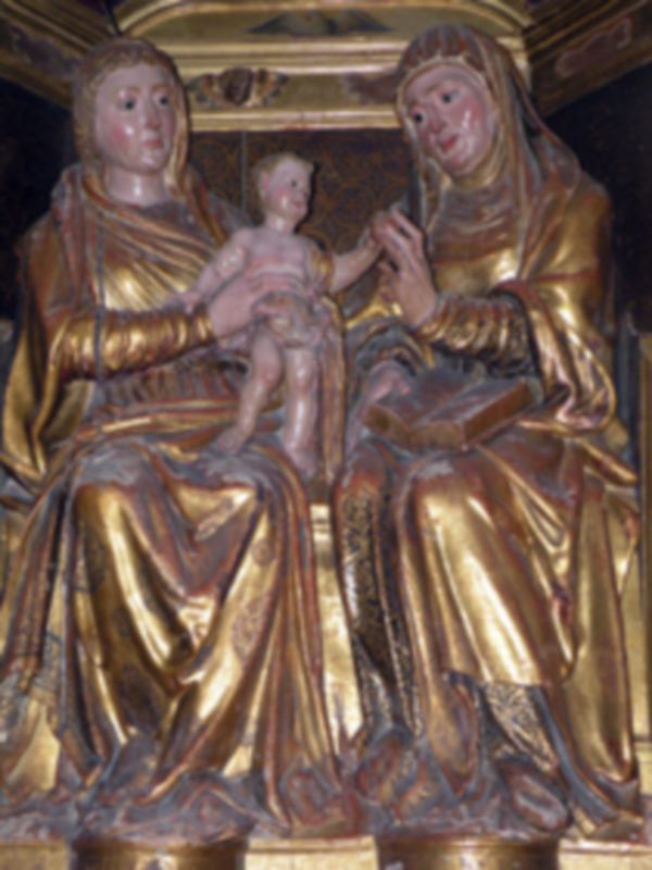 Escultura gótica de la Virgen con el Niño y Santa Ana, dorada y detallada, en un entorno religioso.