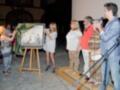 Inauguración de una exposición de arte con la presentación de una obra enmarcada.
