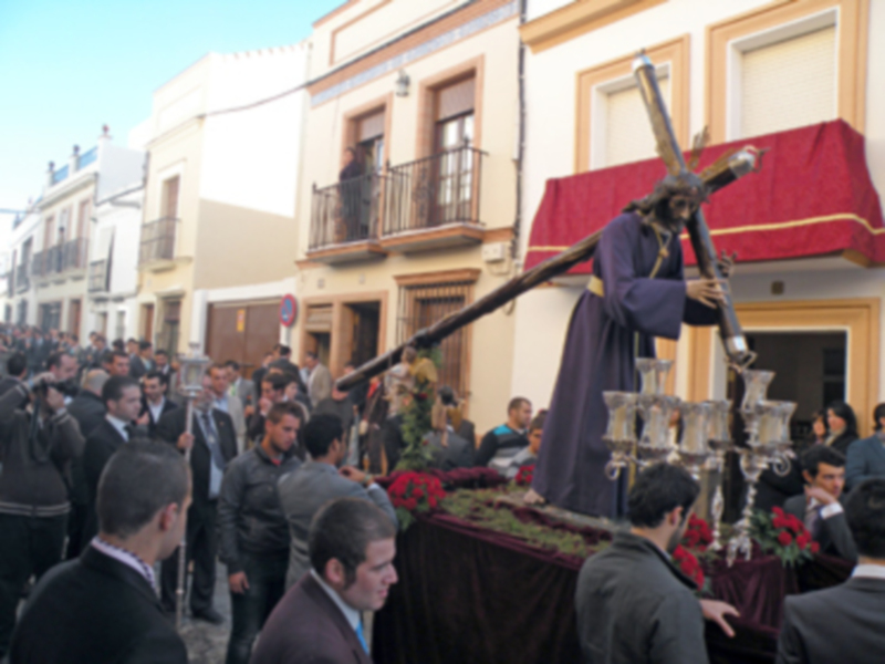 Procesión religiosa con imagen del Cristo de la Buena Muerte en una calle de España.