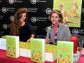 Dos mujeres sonrientes en una firma de libros, con libros titulados 'La Fórmula Femenina' y 'Secretos para sentirte bella'.