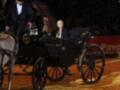 Una imagen de una carroza de caballos en un evento deportivo, con una mujer vestida formalmente sentada en el asiento delantero.