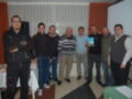 Grupo de hombres posando juntos en una sala de reuniones con una presentación en la pantalla de fondo.