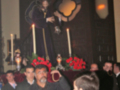 Procesión religiosa con imágenes de santos y velas en un entorno eclesiástico.