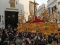 Imaginación de la procesión religiosa en un pueblo andaluz, con una imagen central dorada y roja, rodeada por fieles.