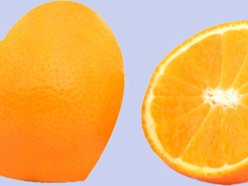 Un naranja entero y otro cortado en dos mitades, mostrando su interior con segmentos y semillas visibles.