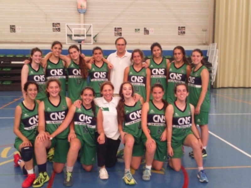 Equipo femenino de baloncesto posando en la cancha, todos vestidos con uniformes verdes y blancos de la escuela CNS.