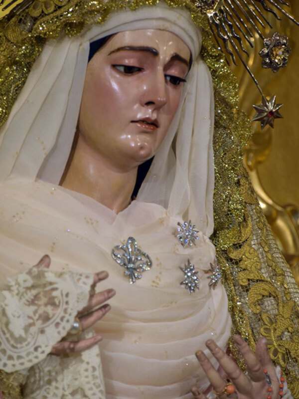 Estatua religiosa con vestimenta dorada y detalles dorados, broches de cristal en la blusa.
