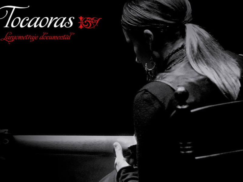 Una mujer con cabello largo y blanco se encuentra de espaldas, mirando hacia la izquierda. La imagen es en blanco y negro, con un fondo oscuro que contrasta con su cabello. La escena sugiere una atmósfera introspectiva o pensativa.