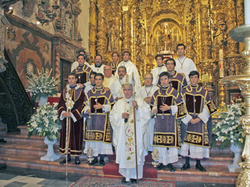 Una procesión religiosa en una iglesia, con sacerdotes vestidos con vestimentas tradicionales y una arquitectura dorada en el fondo.