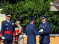 Guardia de honor en una ceremonia militar, con oficiales uniformados en un escenario rojo.