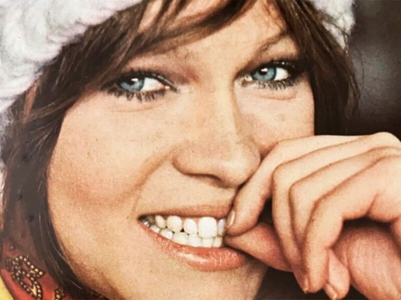 Una mujer con una gorrita de navidad sonriendo y mostrando sus dientes blancos.
