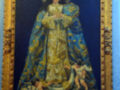 Pintura religiosa de la Virgen María con un niño en sus brazos, vestida con una capa dorada y azul. El marco es dorado y el fondo es azul oscuro.
