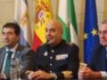 A un grupo de personas sentadas en una mesa, posiblemente en una conferencia o reunión oficial. En el fondo hay banderas de España y la Unión Europea, lo que sugiere un contexto político o diplomático. La escena parece ser formal y de importancia, con los individuos vestidos de manera adecuada para la ocasión.