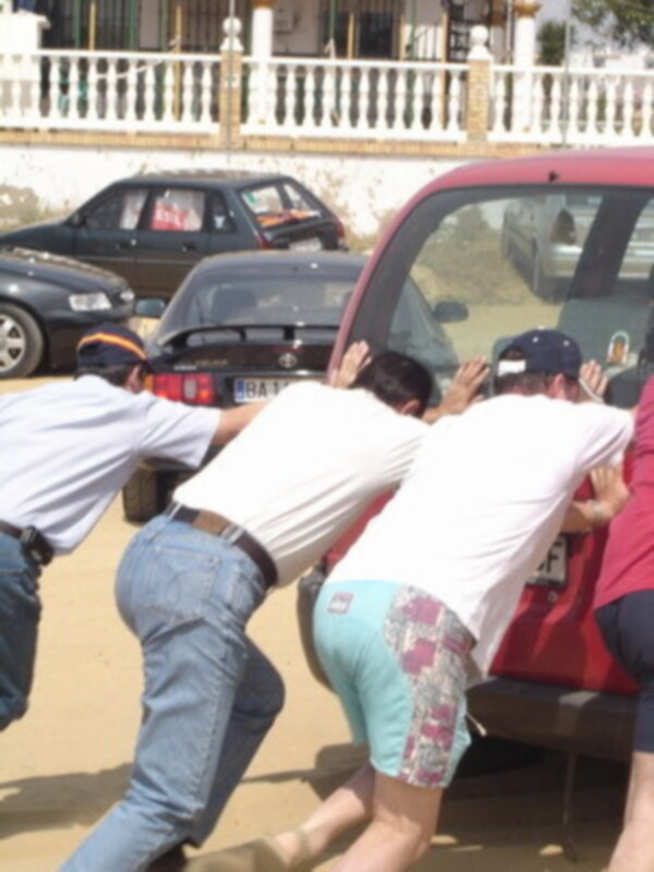 Gente empujando un coche en la playa.