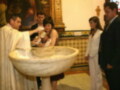 Bautizo en una iglesia con el sacerdote bendiciendo el agua en el pilar de bautismo.