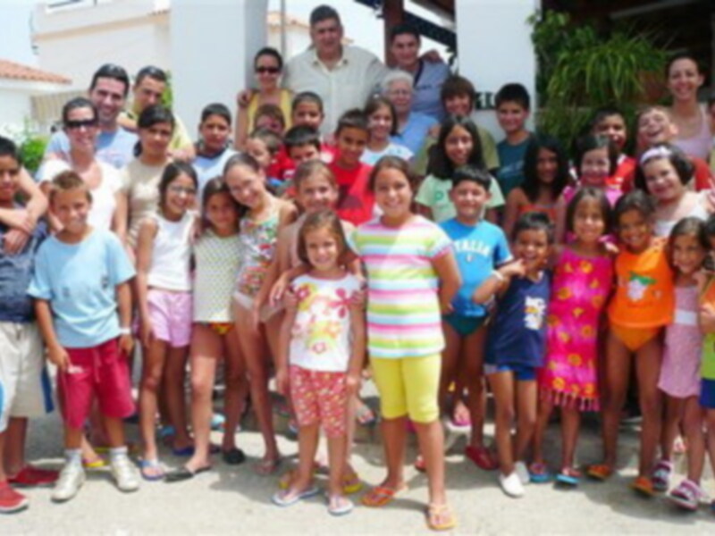 Grupo de niños y adultos sonrientes posando juntos al aire libre.