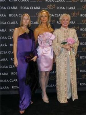 Tres mujeres elegantes posan en un evento de Rosa Clará, con vestidos coloridos y flores.