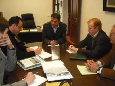 Reunión de trabajo en una oficina, participantes discutiendo y tomando notas.