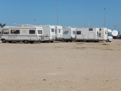 Varios caravanas estacionadas en una zona desértica con cielo azul claro.