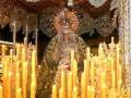 Virgen de la Esperanza en su trono ornado con candelabros y velas iluminando el ambiente.