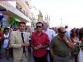 Fiesta religiosa con procesión de la Virgen, gente caminando y observando en una plaza.